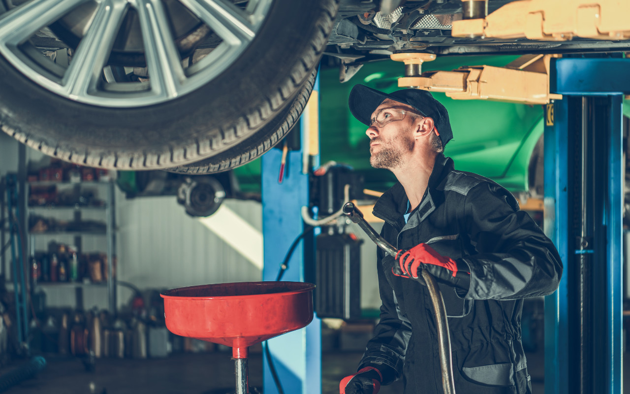 mecanicien qui se prépare à changer l'huile d'un véhicule dans un garage